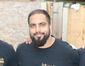 a picture of a bearded man in a black shirt smiling slighly at the camera